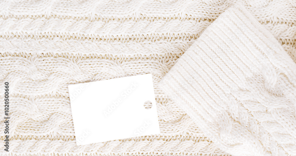 Fototapeta premium Background of top view of textile fabric of woven cozy soft casual sweater of white colour with geometric pattern knitted from warm wool or merino yarn with price tag or label with sale discount