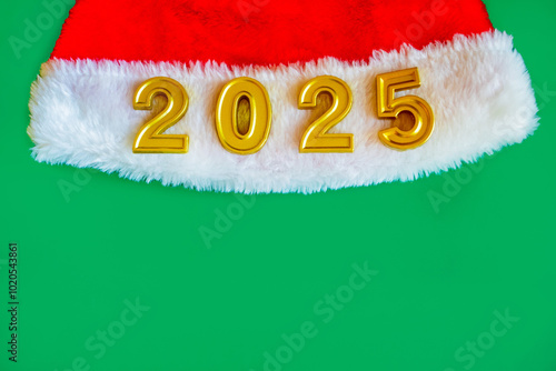 New Year's card with the image of a red fluffy New Year's hat of Santa Claus with a white pompom and white fur with the numbers 2025 and a place for text on a green background photo