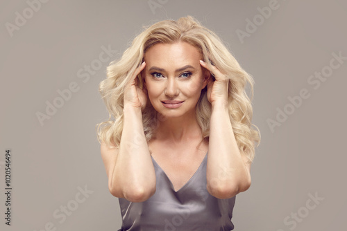 Beauty blonde senior woman with a curly blonde hair and healthy skin on a grey isolated