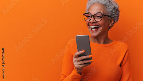 Wallpaper Mural Joyful Senior Woman Using Smartphone Against Vibrant Orange Background, Embracing Technology and Connectivity Torontodigital.ca