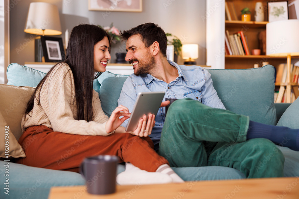 © Impact Photography - Couple doing online shopping using tablet computer and drinking coffee at home