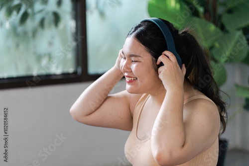 Happy Woman Enjoying Music with Headphones in Bright Room Surrounded by Greenery and Natural Light