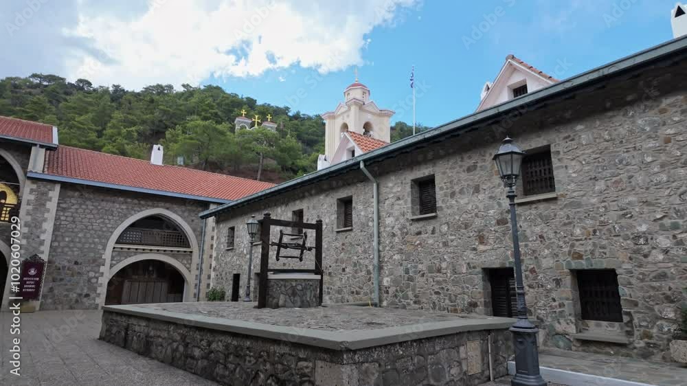 Historic Kikkos Monastery courtyard with stone buildings and a bell tower on a sunny day Historic Kikkos Monastery courtyard with stone buildings and a bell tower on a sunny day
