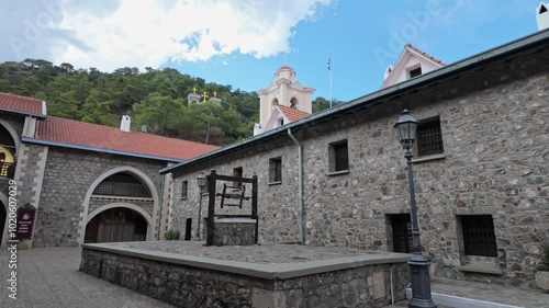 Historic Kikkos Monastery courtyard with stone buildings and a bell tower on a sunny day photo