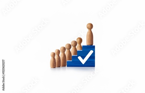 Wooden figures stand on a blue block staircase, the top figure is on the highest step with a white checkmark on the block. photo