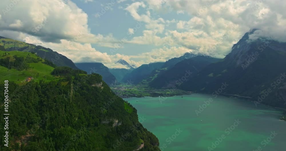 Water transport in Switzerland. Navigating a Swiss Lake. Aerial view steamboat ship on lake Interlaken. Switzerland summer tourism destination. Turquoise blue water. Swiss flag on a passenger ship Water transport in Switzerland. Navigating a Swiss Lake. Aerial view steamboat ship on lake Interlaken. Switzerland summer tourism destination. Turquoise blue water. Swiss flag on a passenger ship