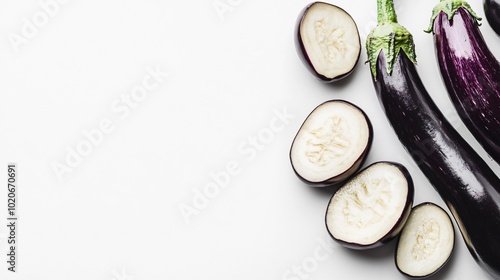 Close up of whole and sliced purple eggplants on a white surface.