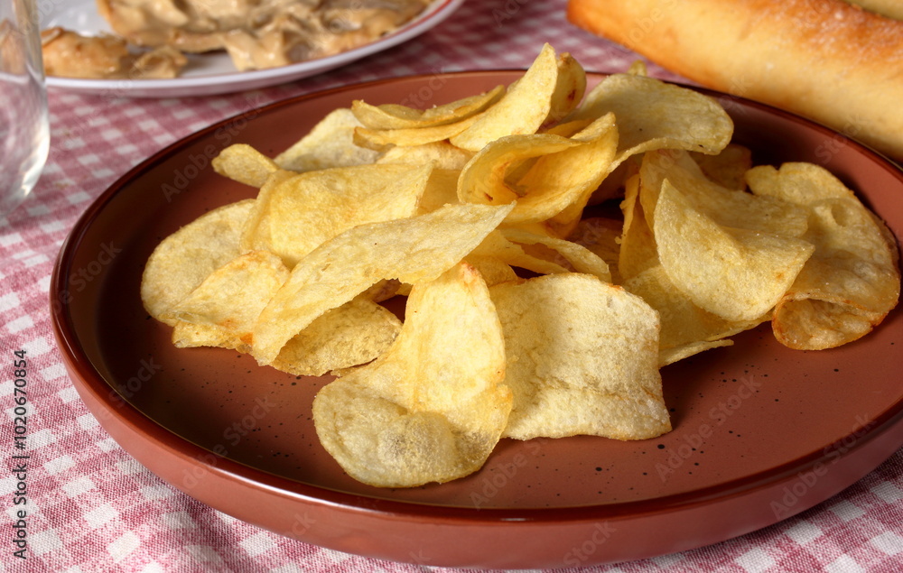 Potato chips arranged on a plate. Savory appetizers for an aperitif with friends. Potato chips arranged on a plate. Savory appetizers for an aperitif with friends.