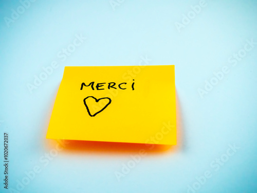 Sticky note with Merci, French for thank you and a little heart shape.