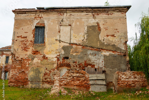 Ruins of the Bykhov castle made of red brick in the park with trees in the background and cloudy sky, Mogilev region, Belarus photo