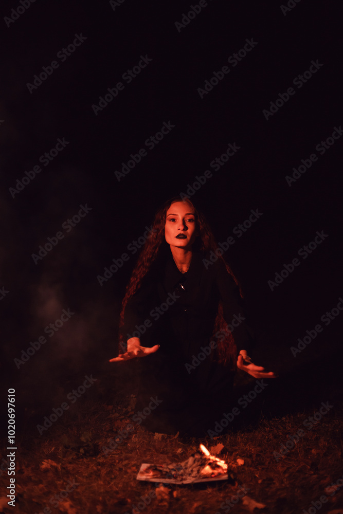 Witch casts a spell over a burning book, mysticism, Halloween, goth woman Witch casts a spell over a burning book, mysticism, Halloween, goth woman