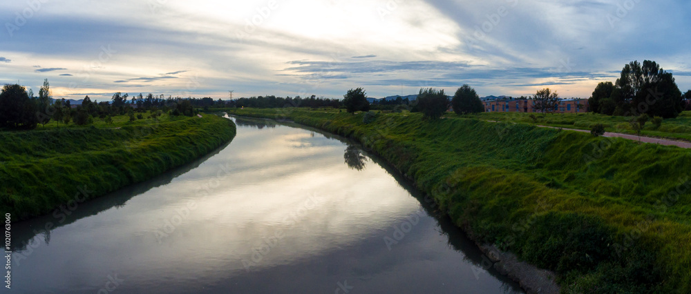 Larger River Flowing Under a Bridge that Connects two Villages across a Dense Vegetation