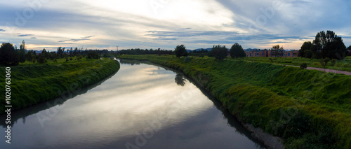 Obraz na płótnie Larger River Flowing Under a Bridge that Connects two Villages across a Dense Vegetation w salonie