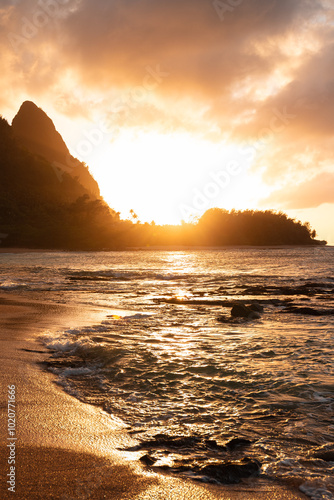 Picturesque sunset at Haena Beach and Tunnels Beach on Kauai with the sun setting behind the hills of Heana State Park (Hawaii, USA)