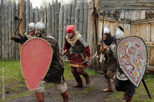 Fotografie Group of medieval reenactors in period costumes engaging in mock battle holding