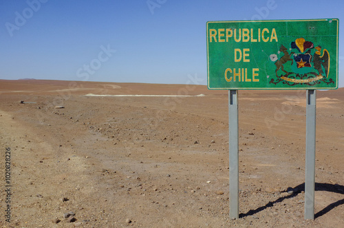 A Border Sign indicating the Republic of Chile prominently stands in the vast Desert Landscape