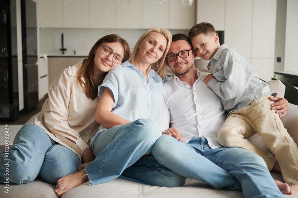 Lovely portrait of family chilling together at home. Big family lying on couch and hugging. Cute moments of time with siblings in modern living room. Lovely portrait of family chilling together at home. Big family lying on couch and hugging. Cute moments of time with siblings in modern living room.