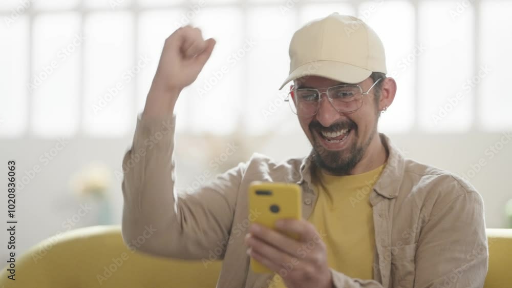 Happy Man celebrates win with smartphone at home. Man reading good news, Victory sitting on couch. High quality 4k footage Happy Man celebrates win with smartphone at home. Man reading good news, Victory sitting on couch. High quality 4k footage