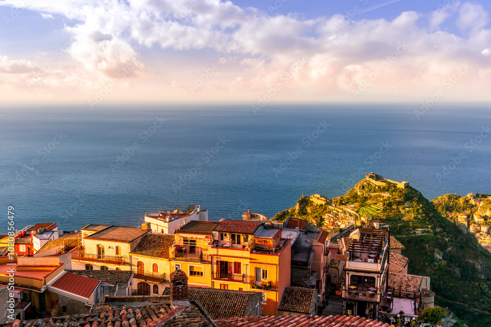 Fototapeta premium beautiful sunset scenic view of a coastline mountain town with nice roofs and streets with mountauns and hills and amazing cloudy sunset on background