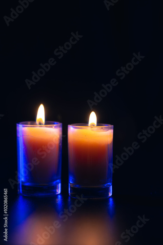 Burning candle on black background with backlight. Memorial Day.