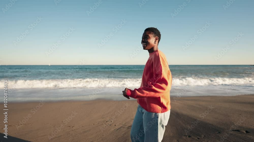 Young African American woman gazes at ocean with bright smile, embodying joy and freedom on beach. Dressed in casual red sweater, she enjoys serene seaside ambiance, with city skyline in background
Young African American woman gazes at ocean with bright smile, embodying joy and freedom on beach. Dressed in casual red sweater, she enjoys serene seaside ambiance, with city skyline in background