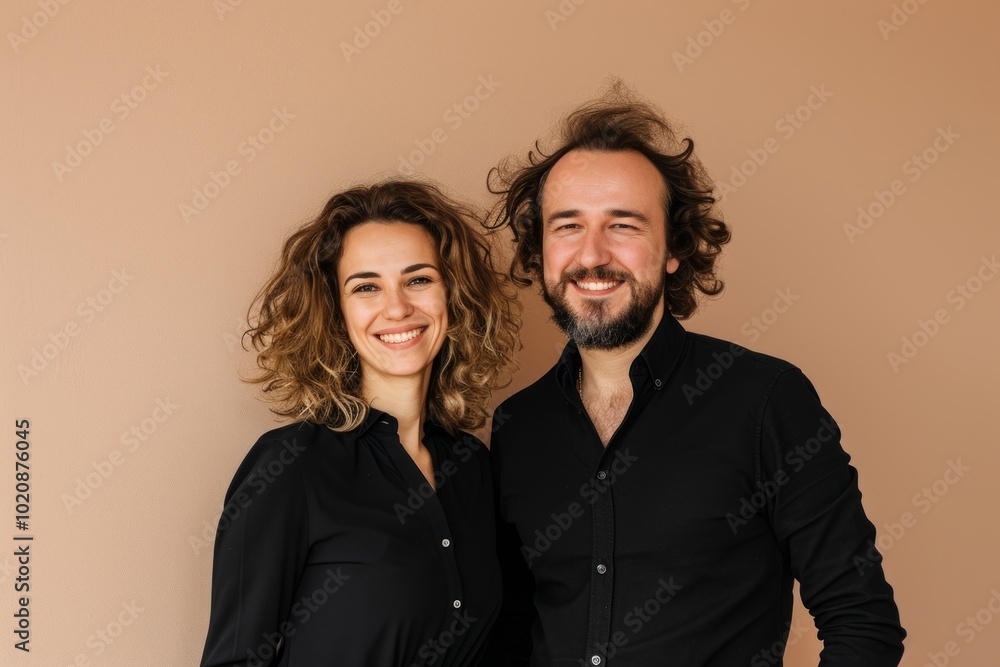 Portrait of a happy couple in black clothes on a beige background Portrait of a happy couple in black clothes on a beige background