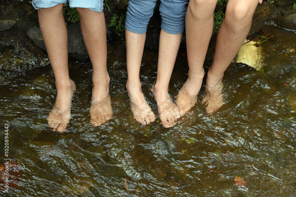 Children playing and having fun with water in the stream. Barefoot children's feet touching the water Children playing and having fun with water in the stream. Barefoot children's feet touching the water