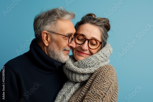 Portrait of a happy senior couple in warm clothes over blue background