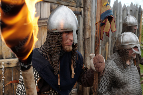 Canvas-taulu Group of reenactors wearing medieval armor standing in front of wooden fort hold