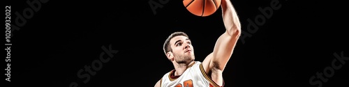 A basketball player is in mid-air, holding a basketball. Concept of athleticism and determination, as the player is focused on the ball and preparing to make a shot