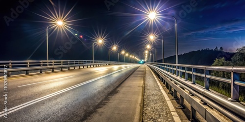 A long, empty road illuminated by streetlights stretches across a bridge, guiding towards a distant horizon under a night sky.