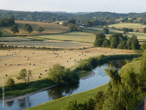 View looking down on the River Wye at Ballingham, Herefordshire on a quiet summer's evening, with bales in the field opposite 