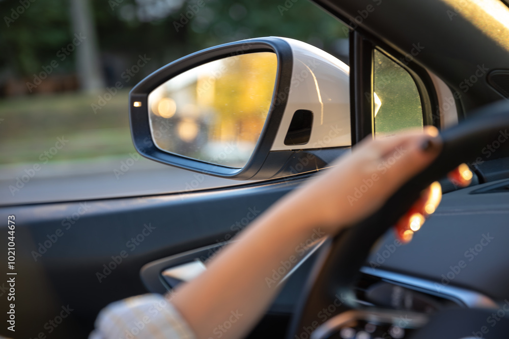 Young woman driving a car. Hands on the wheel. Side mirror in the car. Young woman driving a car. Hands on the wheel. Side mirror in the car.