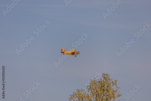 A small sport plane flies low over the ground. The sky is blue photo