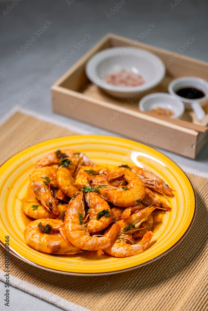 still life, shrimps on a yellow plate, spices and sauce behind them still life, shrimps on a yellow plate, spices and sauce behind them