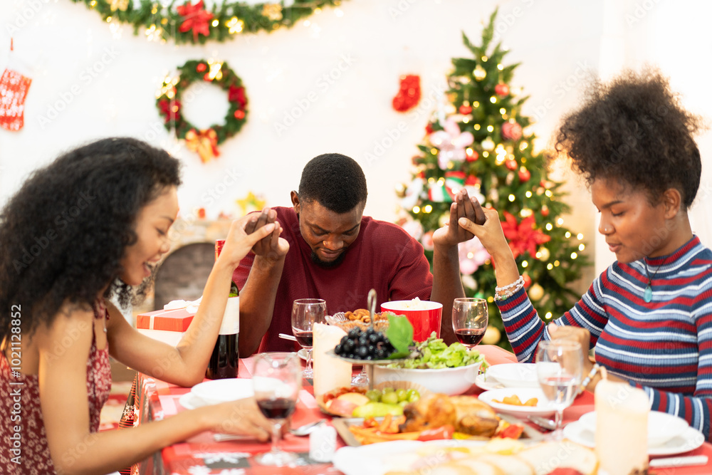 African family holding hands and praying on Thanksgiving or Christmas on holiday during dinner festive. People sharing time together at home African family holding hands and praying on Thanksgiving or Christmas on holiday during dinner festive. People sharing time together at home