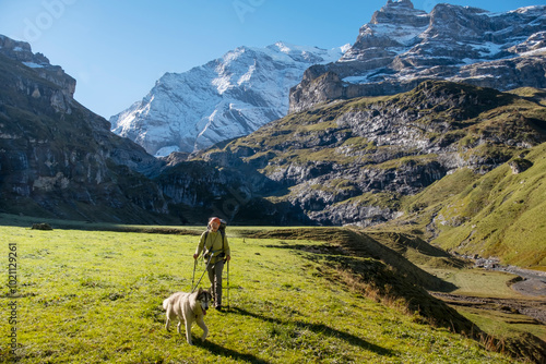 Woman with dog in Switzerland mountain valley Kiental, Berner Oberland Alps. Snow mountains, sunny weather, travel to Swiss, travelling with pet. photo