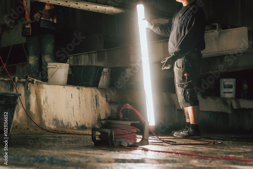 Bauarbeiter mit Lichtröhre auf dunkler Baustelle photo