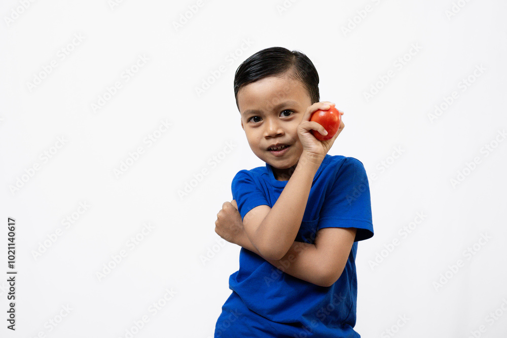 Cute and active Asian boy standing and posing with one red tomato, healthy lifestyle concept, isolated white background. Cute and active Asian boy standing and posing with one red tomato, healthy lifestyle concept, isolated white background.