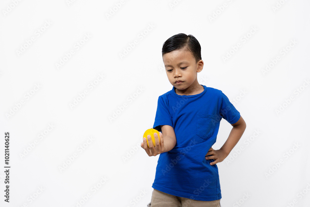 Cute and active Indonesian boy standing posing with a lemon, healthy lifestyle concept, isolated white background.