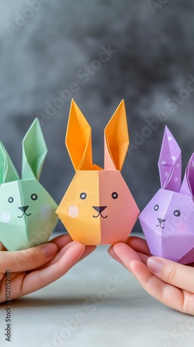 Colorful origami bunnies held gently in hands, showcasing the art of paper folding. These cute pastel rabbits with simple faces bring joy and creativity to Easter crafts. photo