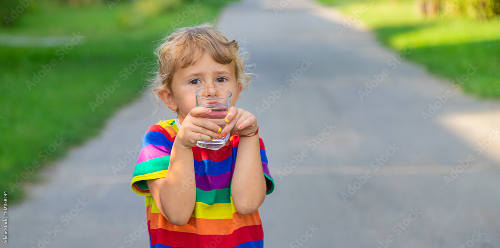 A child drinks water from a glass. Selective focus. A child drinks water from a glass. Selective focus.