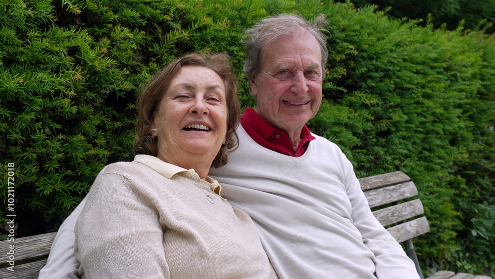 Elderly couple on a bench, laughing together, enjoying a joyful and relaxed moment in a green park setting, highlighting the enduring warmth of their relationship Elderly couple on a bench, laughing together, enjoying a joyful and relaxed moment in a green park setting, highlighting the enduring warmth of their relationship