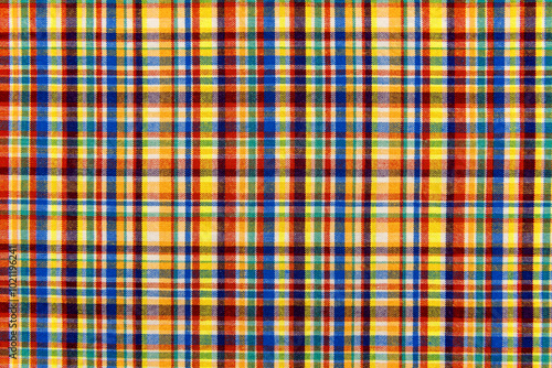 The texture of linen fabric in a large cage of blue, red, yellow and white. Scottish tailoring material. Checkered fabric