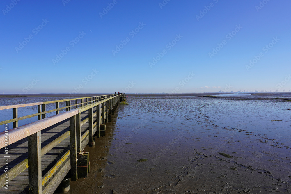 Blick auf den Wattensteg in Burhave an der Nordsee bei Ebbe an einem sonnigen Tag im Herbst Blick auf den Wattensteg in Burhave an der Nordsee bei Ebbe an einem sonnigen Tag im Herbst