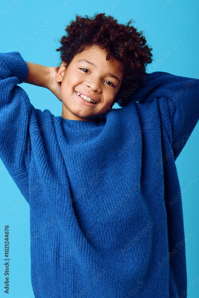 Charming portrait of a joyful african american boy in a blue sweater against a vibrant blue background with a radiant smile Charming portrait of a joyful african american boy in a blue sweater against a vibrant blue background with a radiant smile