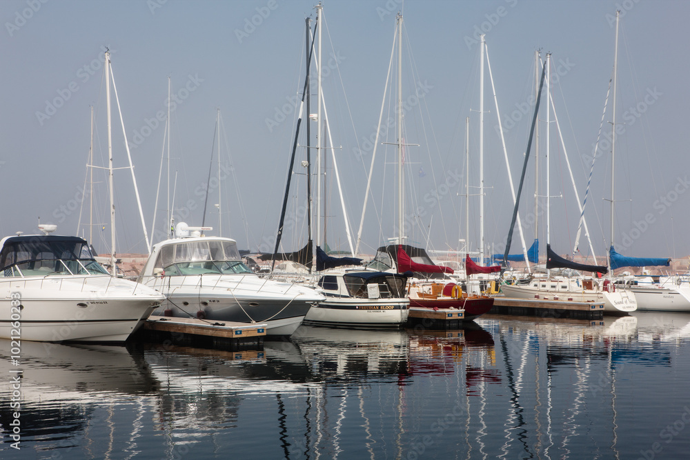 Docked sailboats and power boats cast a reflection on the calm harbor waters of Egg Harbor, Door County, Wisconsin on a late spring morning. Docked sailboats and power boats cast a reflection on the calm harbor waters of Egg Harbor, Door County, Wisconsin on a late spring morning.