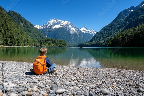 A scenic view of a lake surrounded by mountains, with a person sitting on the shore, embracing the peaceful solitude central to transcendentalist thought photo