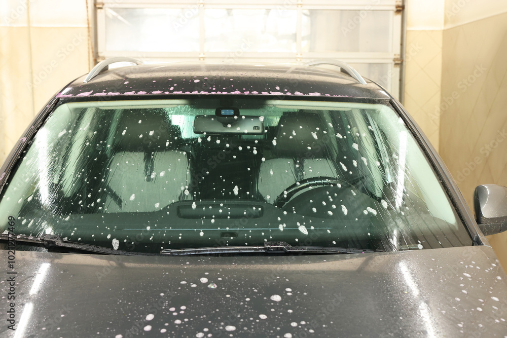 Obraz premium Auto covered with cleaning foam at car wash, closeup
