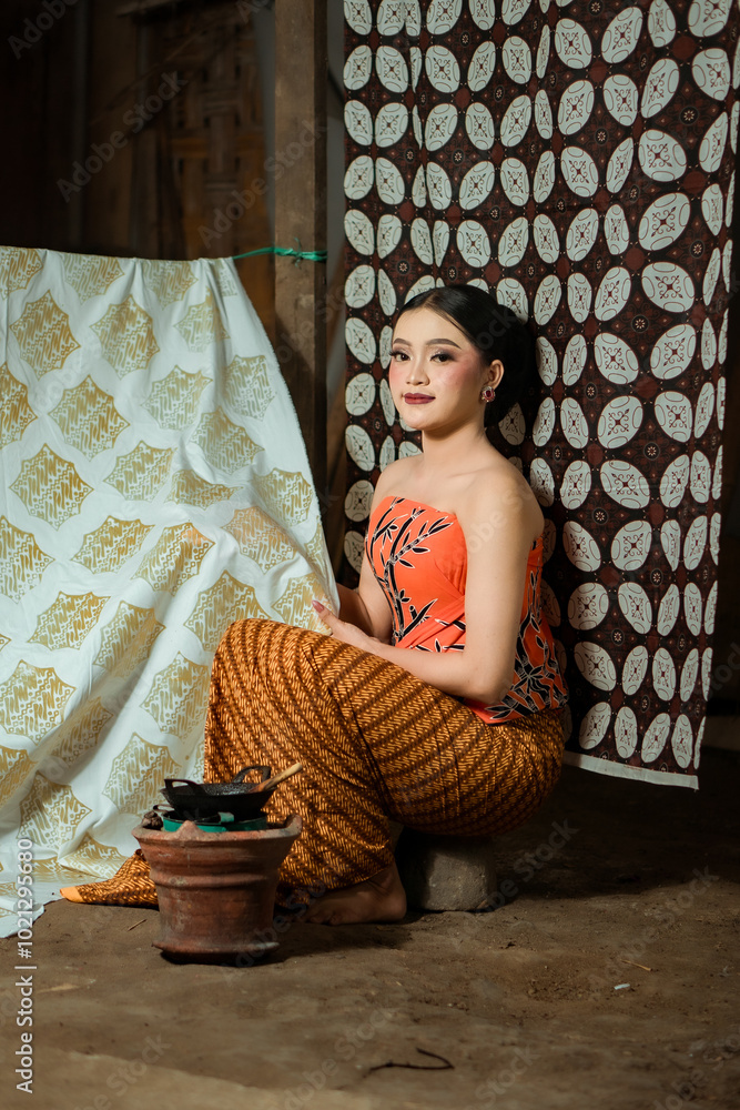 Fototapeta premium Young Indonesian women or fashion models wearing traditional Indonesian clothing or attire with batik motifs from Indonesian culture. Making or painting batik cloth. Making batik cloth.